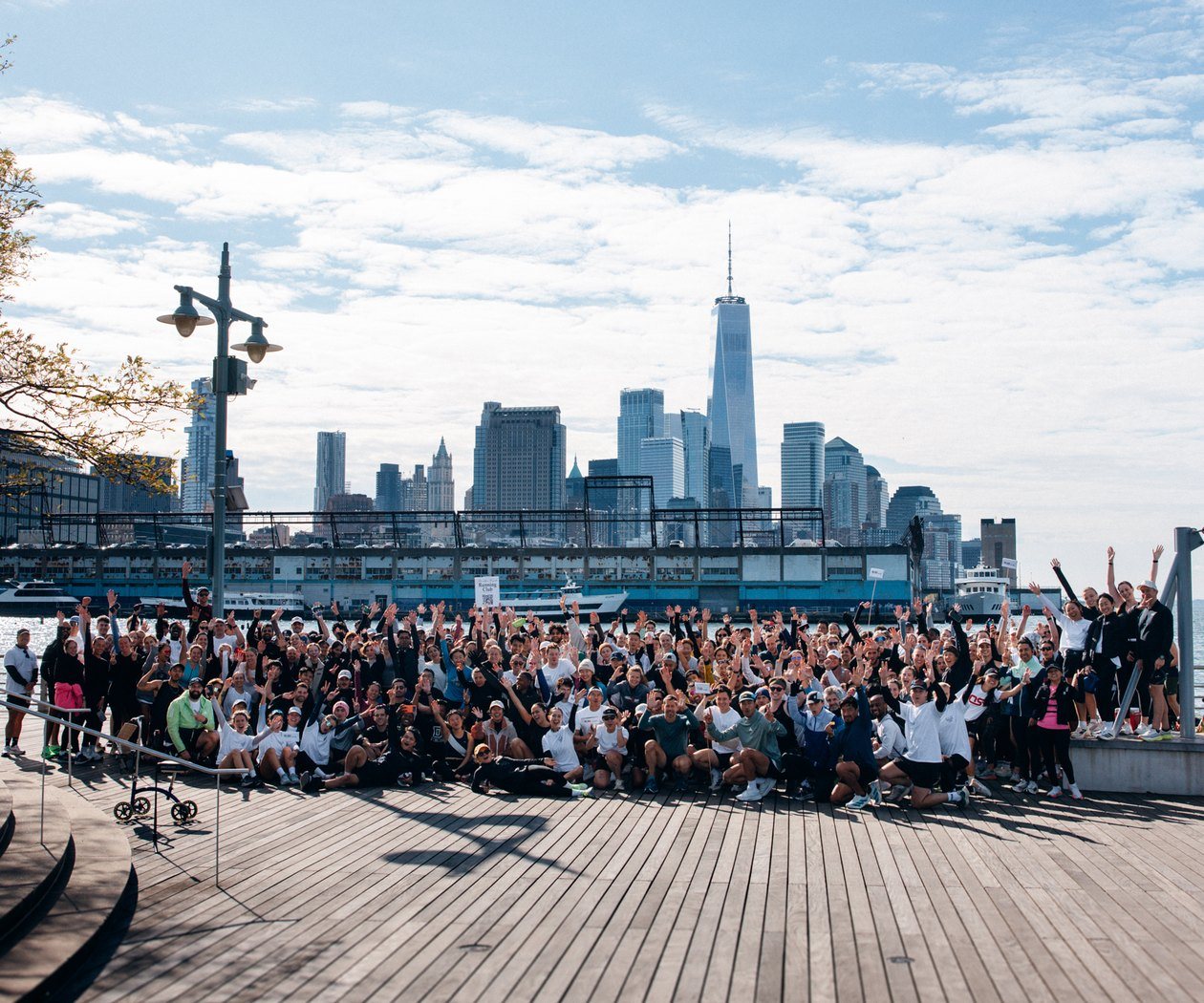 Brooklyn Heights Run Club members on the Brooklyn Bridge Park boardwalk with the Manhattan skyline behind them